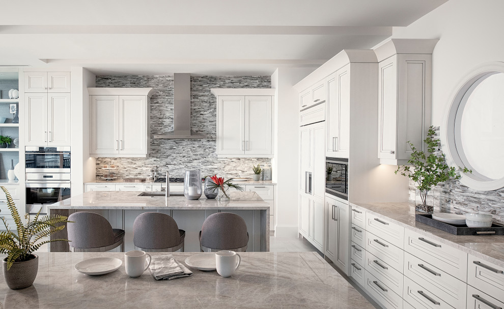 Klassisk inredning av ett mycket stort grå grått l-kök, med en enkel diskho, luckor med infälld panel, vita skåp, grått stänkskydd, stänkskydd i stickkakel, rostfria vitvaror, en köksö och grått golv