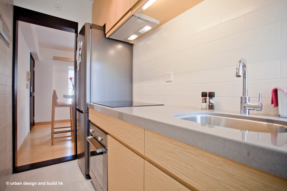 Bild på ett mellanstort funkis kök, med en enkel diskho, släta luckor, skåp i ljust trä, marmorbänkskiva, vitt stänkskydd, stänkskydd i keramik, svarta vitvaror, klinkergolv i keramik och en köksö