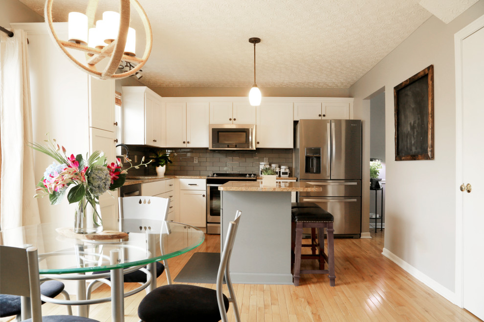 Modern inredning av ett mellanstort beige beige kök, med en nedsänkt diskho, skåp i shakerstil, vita skåp, granitbänkskiva, grått stänkskydd, stänkskydd i tunnelbanekakel, rostfria vitvaror, mellanmörkt trägolv, en köksö och brunt golv