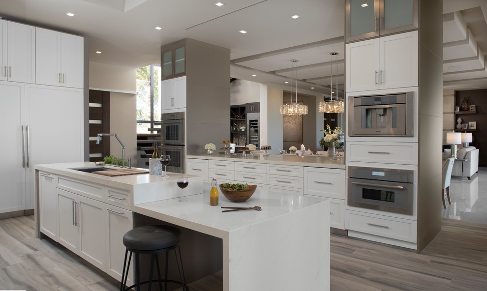 Photo of an expansive contemporary u-shaped kitchen/diner in Orlando with an integrated sink, recessed-panel cabinets, white cabinets, engineered stone countertops, multi-coloured splashback, ceramic splashback, stainless steel appliances, light hardwood flooring, an island and multi-coloured floors.