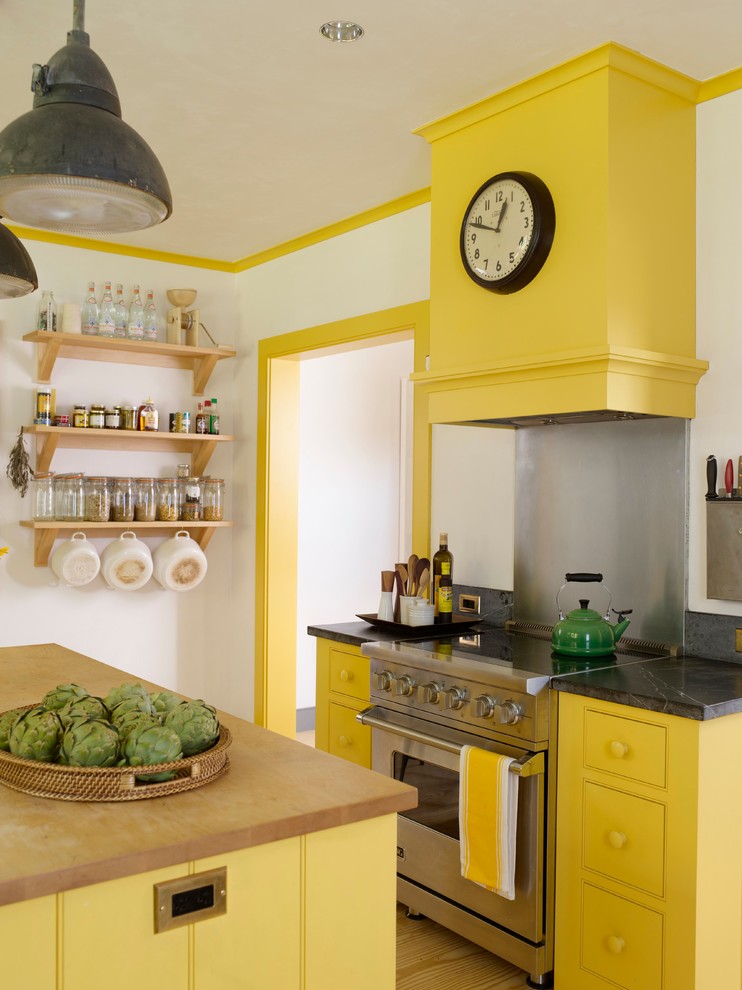 Landhaus Küche mit Kassettenfronten, gelben Schränken, Speckstein-Arbeitsplatte, Küchenrückwand in Metallic und Küchengeräten aus Edelstahl in Bridgeport