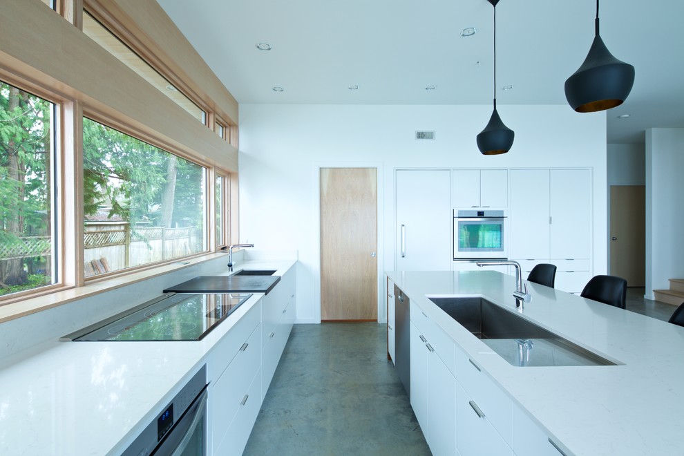 Offene, Mittelgroße Mid-Century Küche in L-Form mit Unterbauwaschbecken, flächenbündigen Schrankfronten, weißen Schränken, Quarzit-Arbeitsplatte, Küchenrückwand in Weiß, weißen Elektrogeräten, Betonboden und Kücheninsel in Vancouver