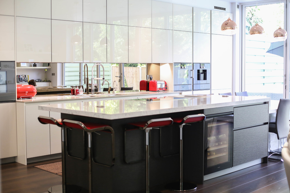Moderne Küche mit flächenbündigen Schrankfronten, weißen Schränken, Rückwand aus Spiegelfliesen, schwarzen Elektrogeräten, dunklem Holzboden und Kücheninsel in London