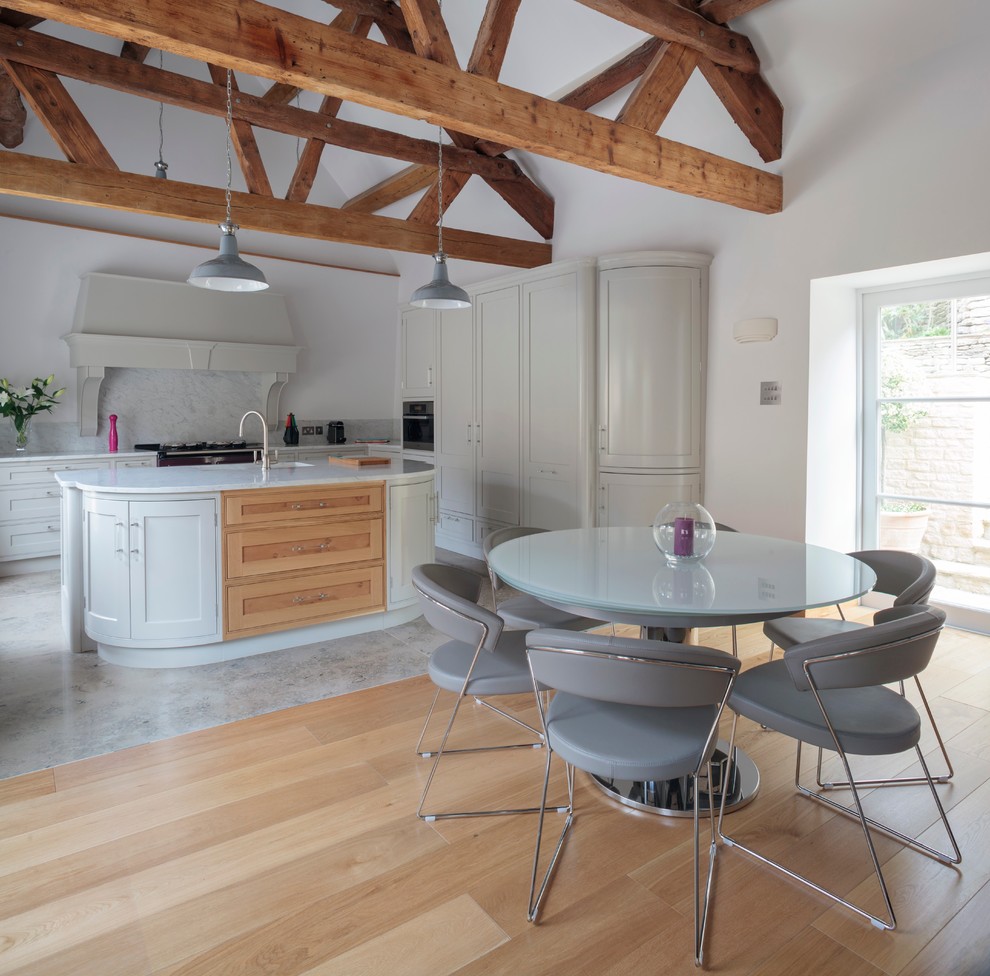 На фото: угловая кухня-гостиная в классическом стиле с фасадами в стиле шейкер, серыми фасадами, белым фартуком и фартуком из каменной плиты