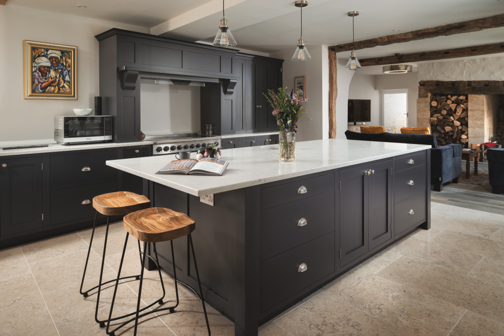 Imagen de cocina tradicional con armarios estilo shaker, puertas de armario negras, electrodomésticos de acero inoxidable, una isla, suelo gris y encimeras blancas