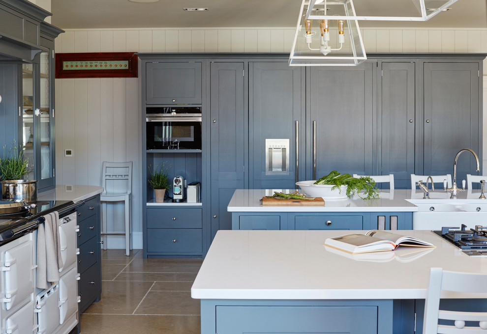 中くらいなカントリー風のおしゃれなマルチアイランドキッチン (エプロンフロントシンク、シェーカースタイル扉のキャビネット、青いキャビネット、パネルと同色の調理設備、ベージュの床、白いキッチンカウンター) の写真
