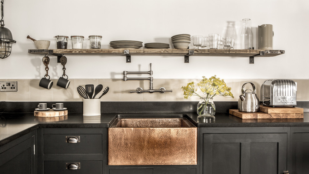 Kitchen - small industrial l-shaped kitchen idea in Cornwall with a farmhouse sink, black cabinets, granite countertops, cement tile backsplash and open cabinets