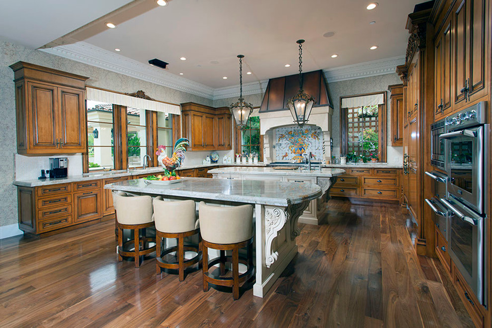 Eat-in kitchen - huge mediterranean u-shaped medium tone wood floor eat-in kitchen idea in Orange County with a farmhouse sink, recessed-panel cabinets, medium tone wood cabinets, limestone countertops, multicolored backsplash, cement tile backsplash, stainless steel appliances and two islands
