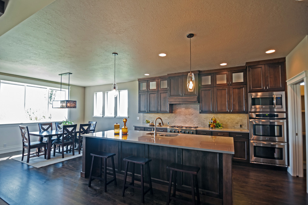 Inspiration for a large craftsman l-shaped dark wood floor eat-in kitchen remodel in Boise with a double-bowl sink, beaded inset cabinets, dark wood cabinets, quartzite countertops, gray backsplash, ceramic backsplash, stainless steel appliances and an island