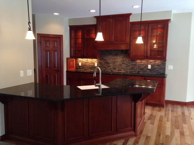 Example of a classic u-shaped light wood floor kitchen design in Milwaukee with glass-front cabinets, gray backsplash, matchstick tile backsplash and no island