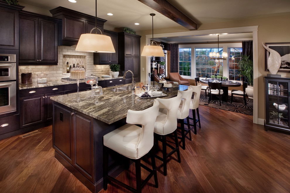 Example of a tuscan eat-in kitchen design in Denver with a double-bowl sink, raised-panel cabinets, dark wood cabinets, beige backsplash and subway tile backsplash