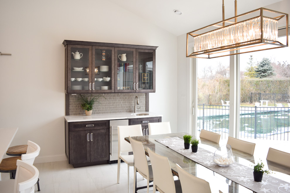 Eat-in kitchen - mid-sized transitional single-wall marble floor eat-in kitchen idea in New York with an undermount sink, glass-front cabinets, dark wood cabinets, quartz countertops, gray backsplash, glass tile backsplash, stainless steel appliances and an island
