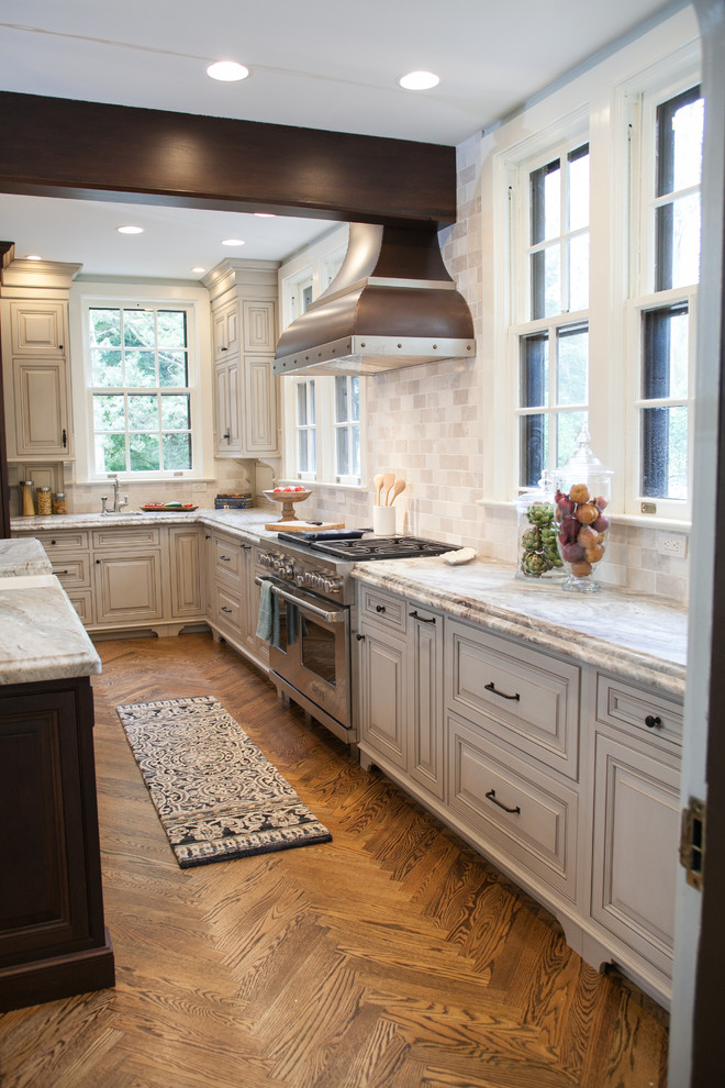 Enclosed kitchen - large traditional l-shaped medium tone wood floor enclosed kitchen idea in Philadelphia with a farmhouse sink, raised-panel cabinets, granite countertops, beige backsplash, paneled appliances and an island