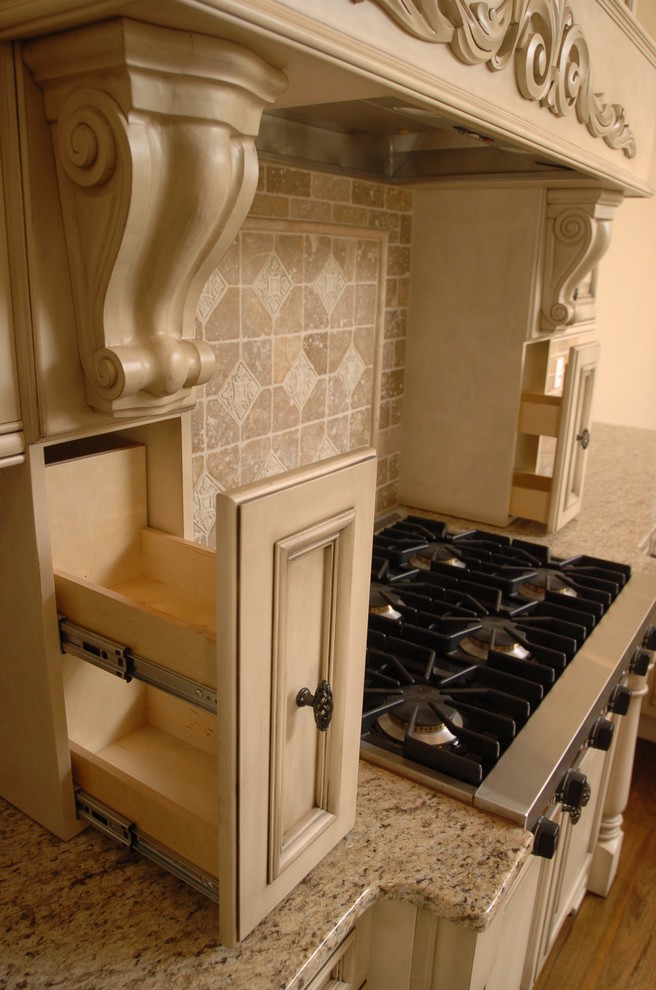 Immagine di una cucina chic con ante in stile shaker, ante con finitura invecchiata, paraspruzzi beige, paraspruzzi con piastrelle in pietra e elettrodomestici in acciaio inossidabile