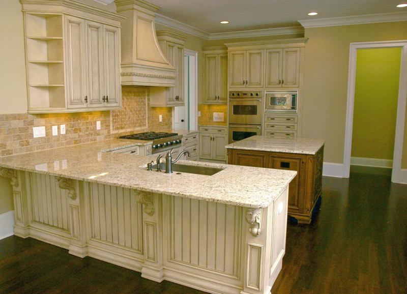 Klassisk inredning av ett stort kök, med skåp i slitet trä, marmorbänkskiva, beige stänkskydd, rostfria vitvaror, mellanmörkt trägolv, en köksö, en undermonterad diskho, luckor med infälld panel och stänkskydd i keramik