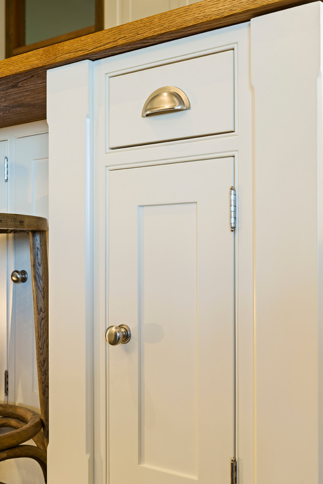 Modelo de cocina clásica con fregadero bajoencimera, armarios estilo shaker, puertas de armario blancas, salpicadero de azulejos tipo metro y suelo de pizarra