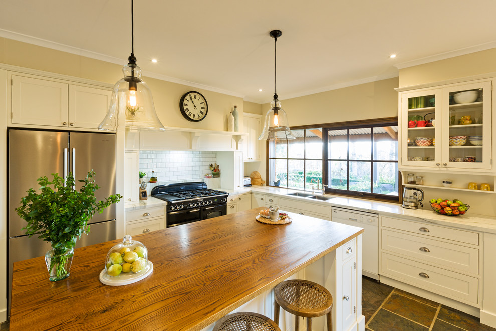 Foto på ett lantligt kök, med en dubbel diskho, träbänkskiva, skiffergolv och en köksö