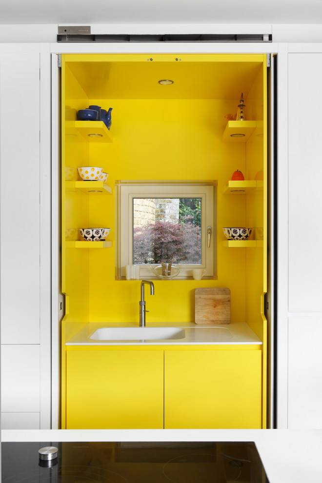 Ispirazione per una cucina design di medie dimensioni con lavello da incasso, ante lisce, ante gialle, top in laminato, paraspruzzi giallo, elettrodomestici in acciaio inossidabile, pavimento in gres porcellanato e 2 o più isole