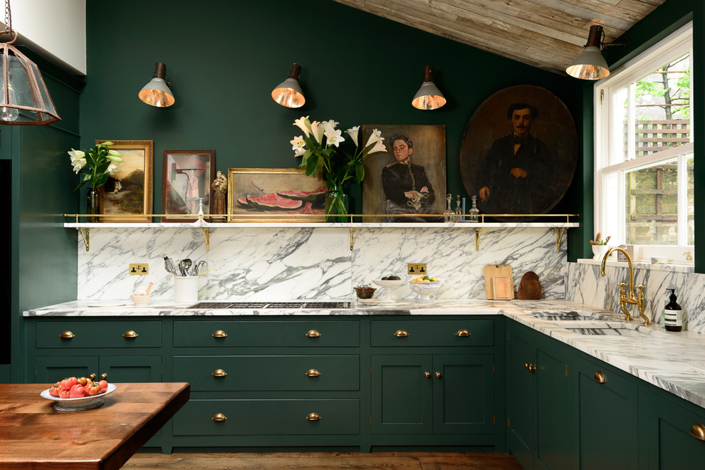 Inredning av ett klassiskt stort kök, med en nedsänkt diskho, släta luckor, gröna skåp, marmorbänkskiva, vitt stänkskydd och mörkt trägolv
