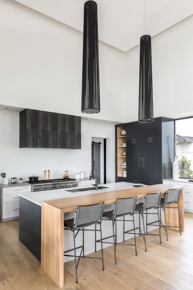 Moderne Küche mit Unterbauwaschbecken, flächenbündigen Schrankfronten, grauen Schränken, Küchengeräten aus Edelstahl, hellem Holzboden und beigem Boden in Austin