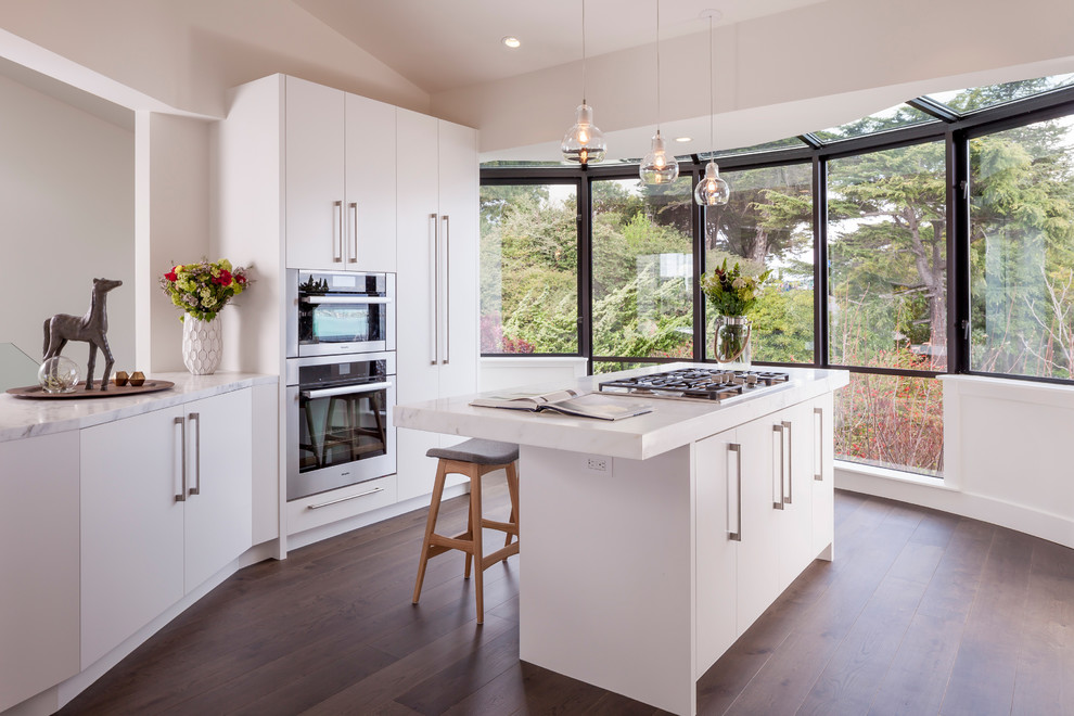 Moderne Küche mit flächenbündigen Schrankfronten, Küchengeräten aus Edelstahl, braunem Holzboden und Kücheninsel in San Francisco
