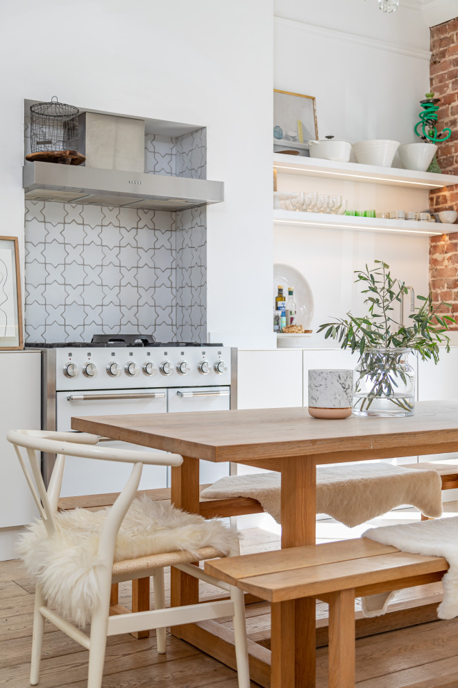Foto di una cucina abitabile tradizionale con ante lisce, ante bianche, paraspruzzi bianco, elettrodomestici bianchi, pavimento in legno massello medio, pavimento marrone e top bianco