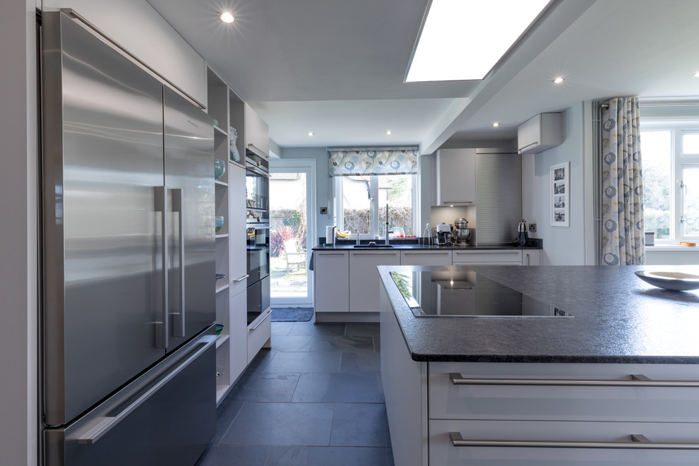 Design ideas for a large contemporary l-shaped kitchen/diner in Hampshire with an integrated sink, grey cabinets, granite worktops, slate flooring, an island, flat-panel cabinets and stainless steel appliances.