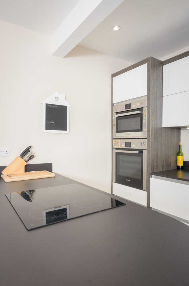 Inspiration pour une petite cuisine design avec des portes de placard blanches et un électroménager en acier inoxydable.
