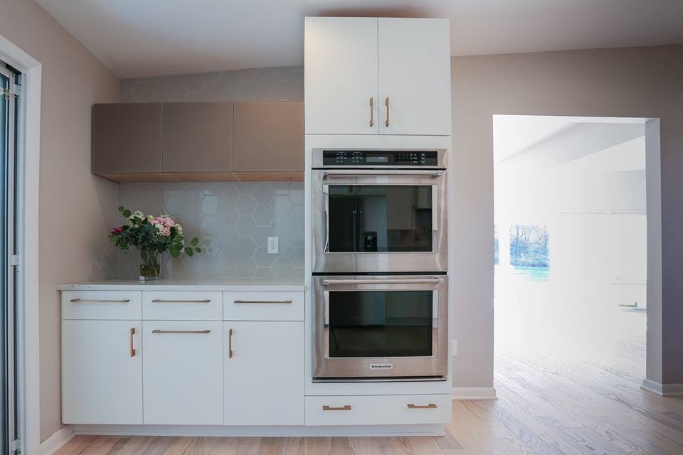 Example of a large trendy l-shaped light wood floor and beige floor enclosed kitchen design in Baltimore with an undermount sink, flat-panel cabinets, white cabinets, marble countertops, gray backsplash, ceramic backsplash, stainless steel appliances, an island and white countertops