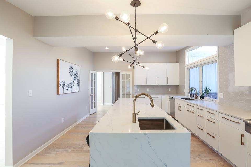 Example of a large trendy l-shaped light wood floor and beige floor enclosed kitchen design in Baltimore with an undermount sink, flat-panel cabinets, white cabinets, marble countertops, gray backsplash, ceramic backsplash, stainless steel appliances, an island and white countertops