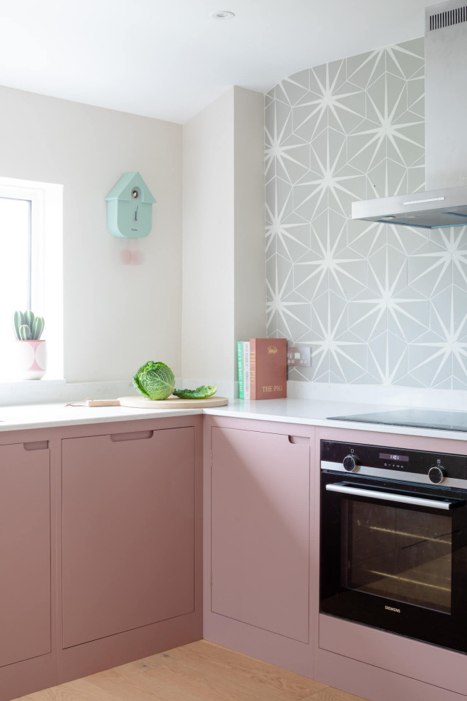 Design ideas for a medium sized scandi l-shaped kitchen/diner in Other with flat-panel cabinets, pink cabinets, engineered stone countertops, light hardwood flooring, no island and white worktops.