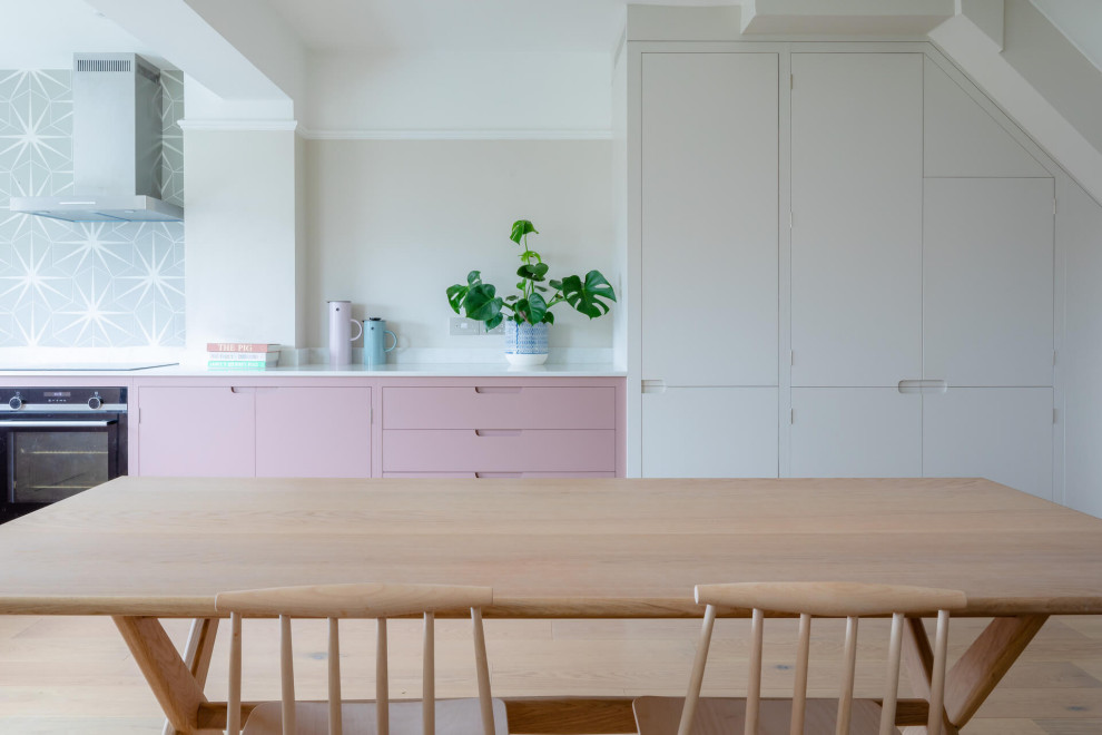 Ejemplo de cocina escandinava de tamaño medio sin isla con armarios con paneles lisos, puertas de armarios rosa, encimera de cuarzo compacto, suelo de madera clara y encimeras blancas