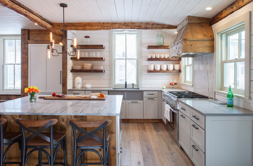 Rustic l-shaped kitchen in Denver with a submerged sink, shaker cabinets, grey cabinets, grey splashback, marble splashback, integrated appliances, medium hardwood flooring, an island, brown floors and grey worktops.