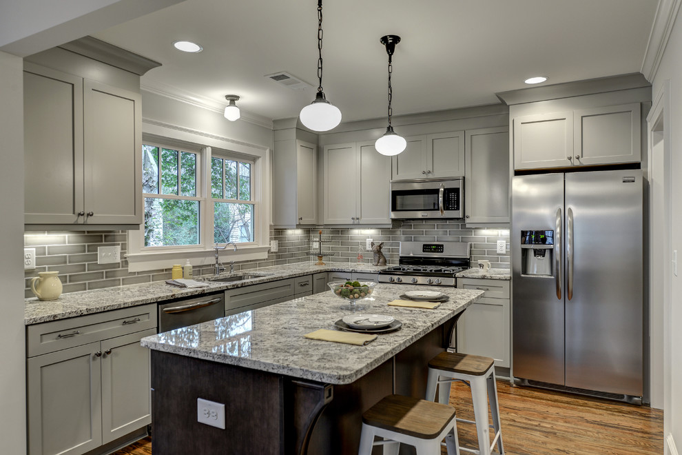 Small elegant l-shaped medium tone wood floor kitchen photo in Atlanta with an undermount sink, shaker cabinets, gray cabinets, granite countertops, gray backsplash, ceramic backsplash, stainless steel appliances and an island