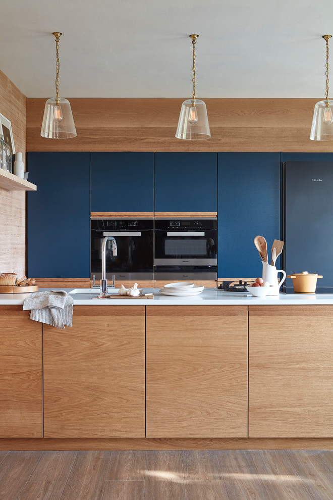 Zweizeilige, Kleine Moderne Küche mit flächenbündigen Schrankfronten, blauen Schränken, Quarzit-Arbeitsplatte, Kücheninsel und dunklem Holzboden in London