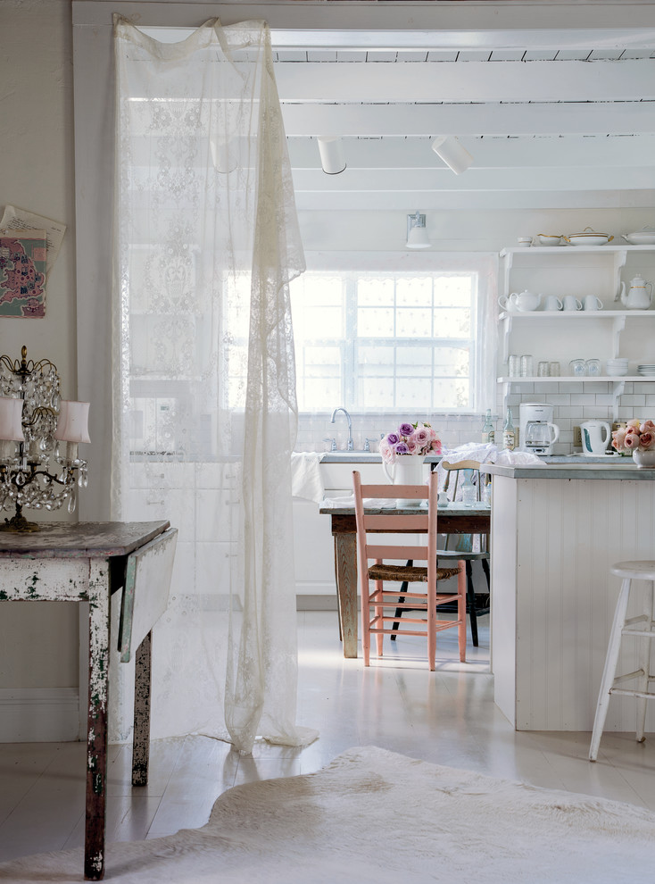 Ejemplo de cocina comedor romántica con armarios abiertos, puertas de armario blancas, salpicadero blanco, salpicadero de azulejos tipo metro, electrodomésticos blancos y una isla