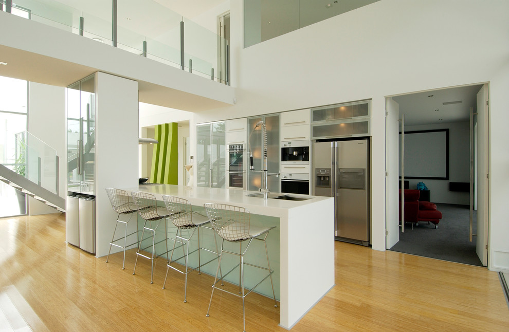 Esempio di una cucina contemporanea con lavello sottopiano, ante di vetro, elettrodomestici in acciaio inossidabile, pavimento in legno massello medio, pavimento marrone e top bianco