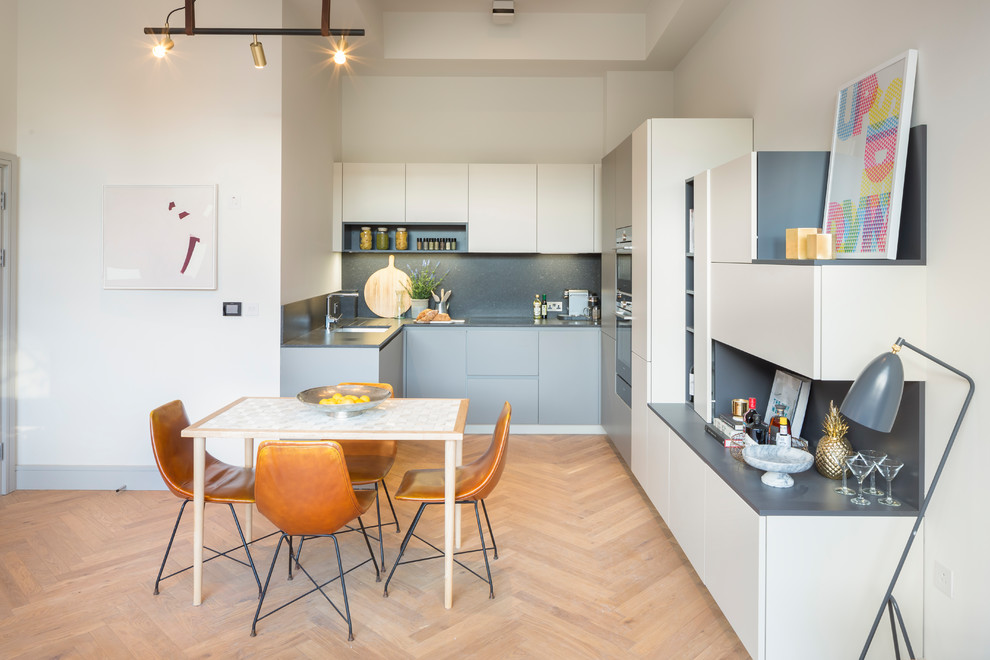 Contemporary u-shaped kitchen/diner in London with a submerged sink, flat-panel cabinets, grey cabinets, grey splashback, integrated appliances, light hardwood flooring, no island, beige floors and grey worktops.