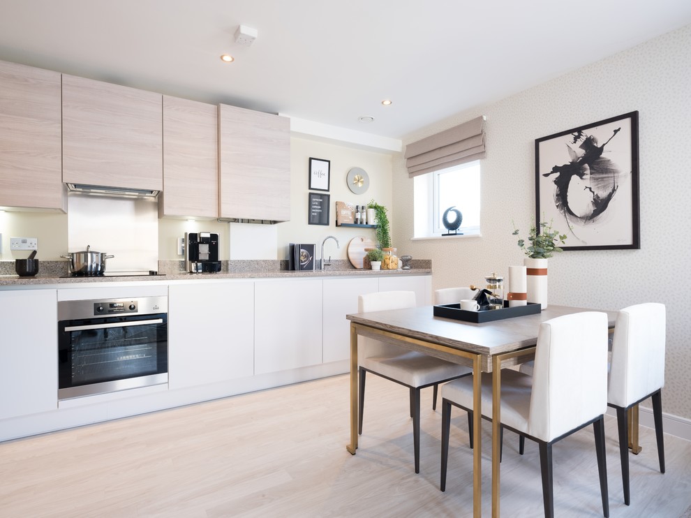 Contemporary l-shaped kitchen in Other with a submerged sink, flat-panel cabinets, white cabinets, white splashback, stainless steel appliances, light hardwood flooring, no island, beige floors and grey worktops.