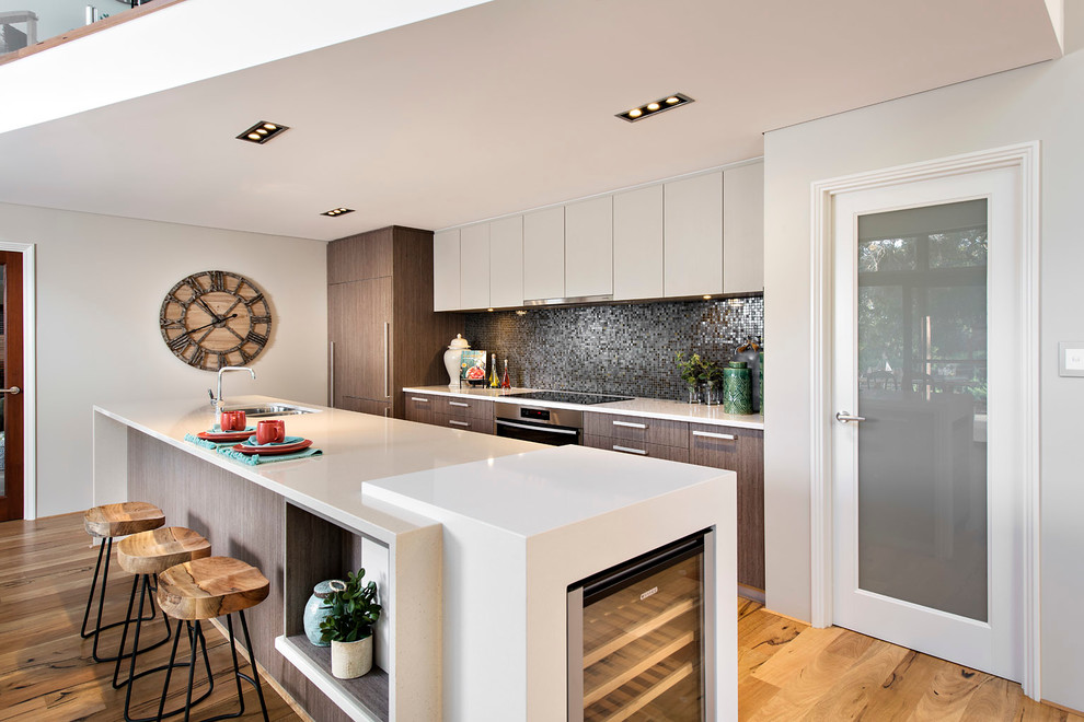 Exempel på ett modernt kök, med en dubbel diskho, släta luckor, vita skåp, stänkskydd i mosaik, integrerade vitvaror, ljust trägolv, en köksö och grått stänkskydd