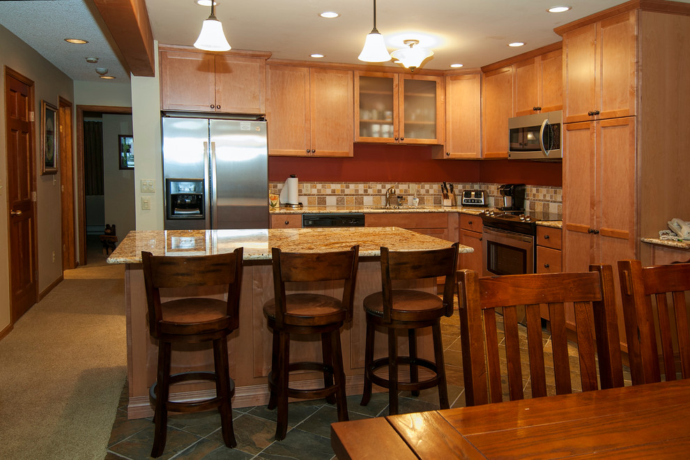 Bild på ett mellanstort rustikt kök, med luckor med infälld panel, skåp i ljust trä, granitbänkskiva, brunt stänkskydd, stänkskydd i keramik, rostfria vitvaror, klinkergolv i keramik och en köksö