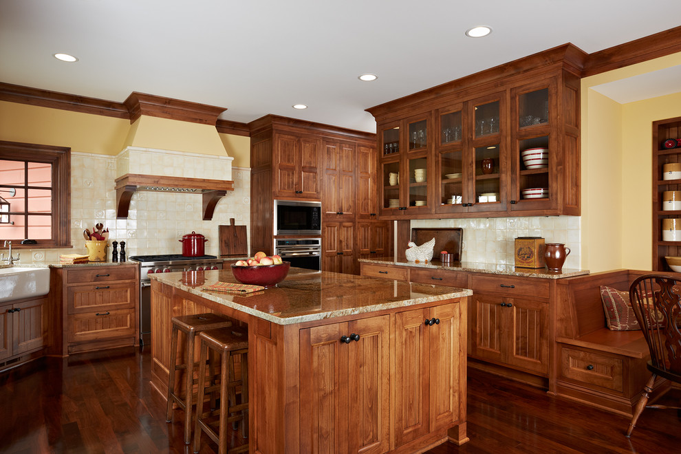 Rustik inredning av ett avskilt, stort kök, med en rustik diskho, luckor med infälld panel, skåp i mellenmörkt trä, granitbänkskiva, stänkskydd i keramik, rostfria vitvaror, mellanmörkt trägolv, en köksö och beige stänkskydd