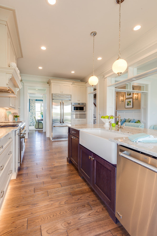 Example of an arts and crafts medium tone wood floor kitchen design in Other with a farmhouse sink, shaker cabinets, beige cabinets, quartz countertops, beige backsplash, mosaic tile backsplash, stainless steel appliances and an island