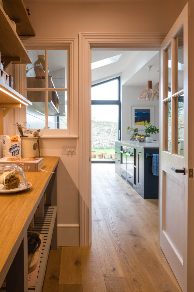 Foto på ett mellanstort funkis vit kök med öppen planlösning, med en nedsänkt diskho, skåp i shakerstil, blå skåp, bänkskiva i kvartsit, ljust trägolv och en köksö