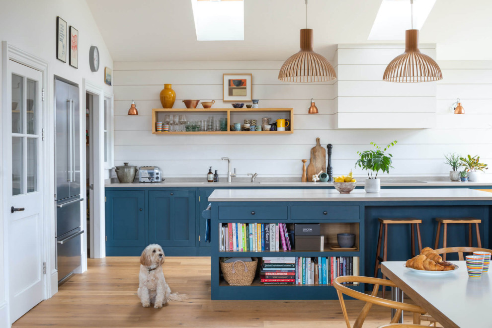 Photo of a medium sized traditional open plan kitchen in Other with a built-in sink, shaker cabinets, blue cabinets, quartz worktops, light hardwood flooring, an island and white worktops.
