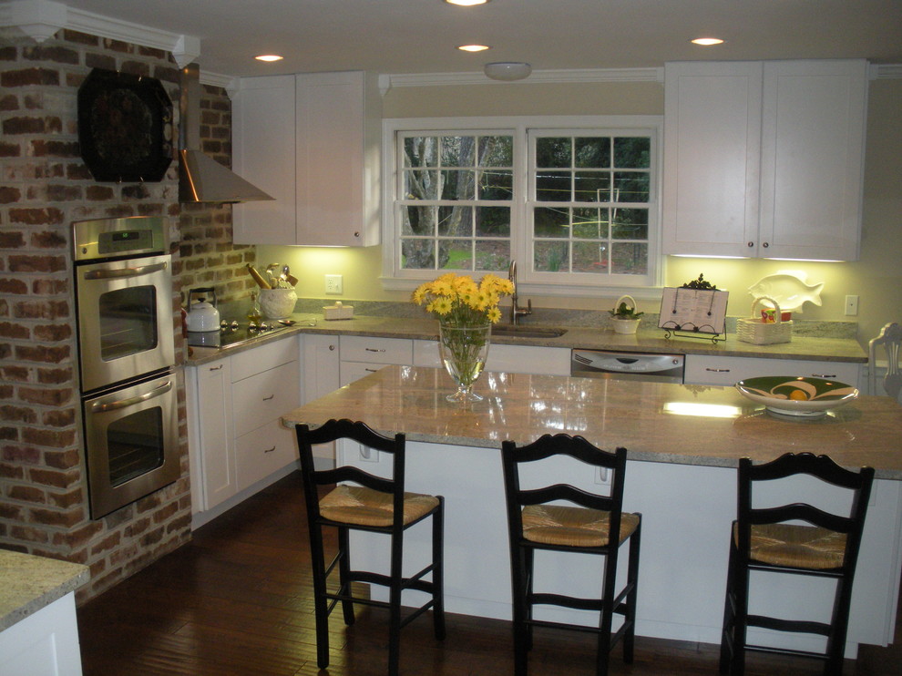 Example of a mid-sized trendy l-shaped dark wood floor eat-in kitchen design in Atlanta with a single-bowl sink, flat-panel cabinets, white cabinets, red backsplash, stainless steel appliances and an island