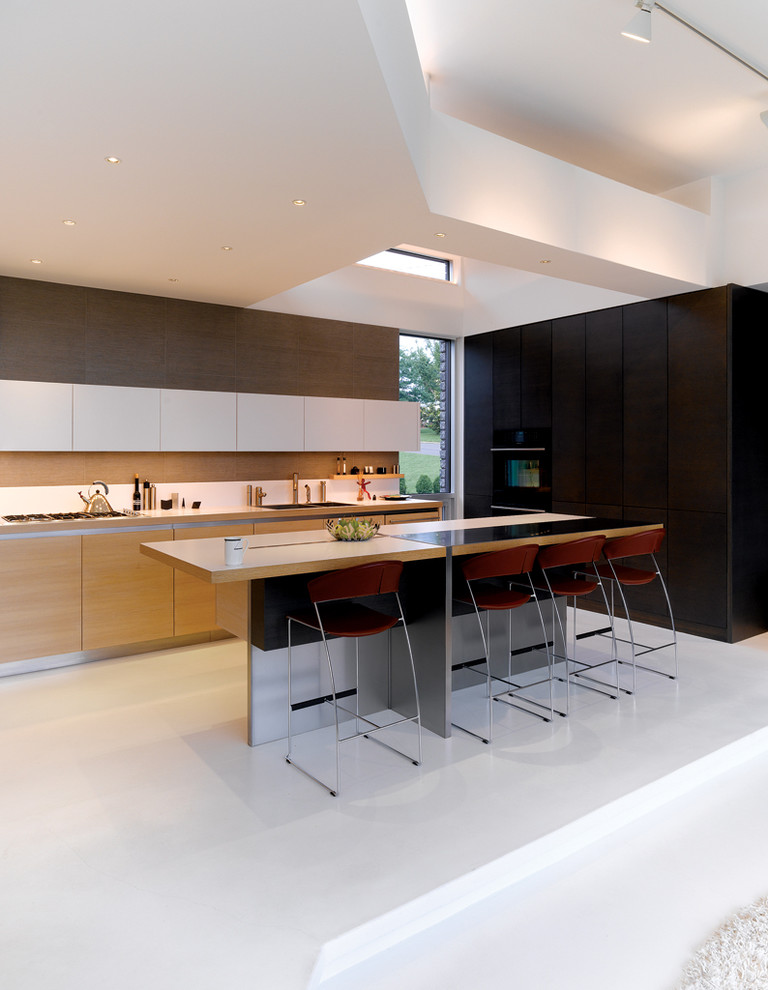 На фото: угловая кухня в стиле модернизм с плоскими фасадами, светлыми деревянными фасадами и барной стойкой
