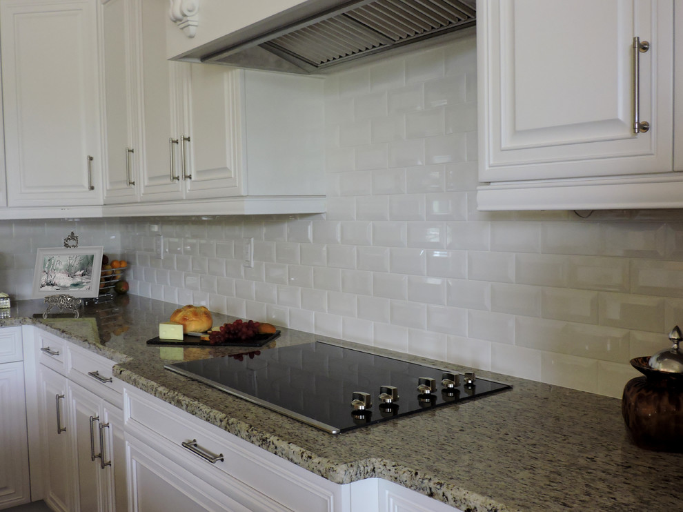 Imagen de cocina minimalista con armarios con paneles empotrados, puertas de armario blancas y salpicadero de azulejos tipo metro