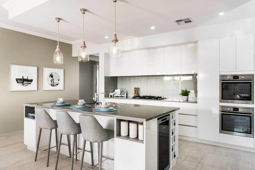Inspiration for a large contemporary galley porcelain tile and white floor open concept kitchen remodel in Perth with an undermount sink, flat-panel cabinets, white cabinets, quartz countertops, white backsplash, glass sheet backsplash, stainless steel appliances and an island