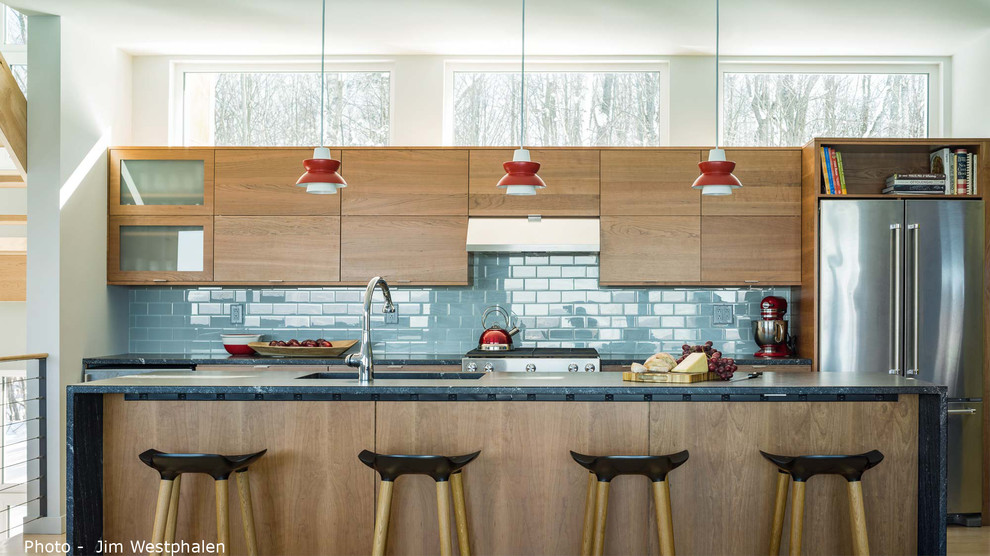 Exempel på ett mellanstort modernt kök, med en enkel diskho, släta luckor, skåp i mellenmörkt trä, granitbänkskiva, blått stänkskydd, stänkskydd i glaskakel, rostfria vitvaror, ljust trägolv, en köksö och gult golv